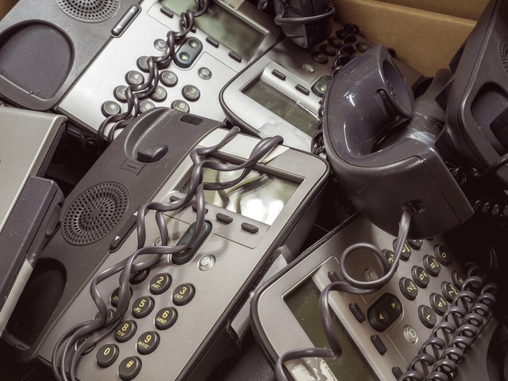 A tangle of old, dusty business phone systems in a box.