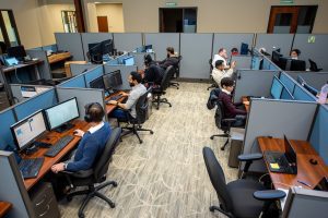 Office workers busy at their desks in a modern cubicle workspace.