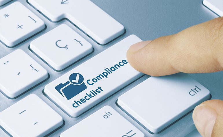 A finger is pressing a key labeled "Compliance checklist" on a white keyboard.