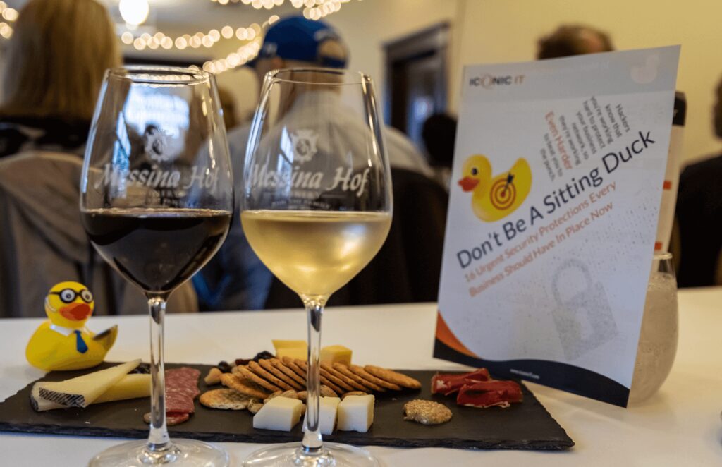 Two wine glasses with red and white wine next to a platter of cheese, crackers, and dried meats. A flyer with a duck image in the background reads Don't Be A Sitting Duck.