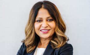 A woman with shoulder-length hair, wearing a dark blazer and smiling warmly.
