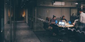 Professionals in a meeting room working late with laptops.