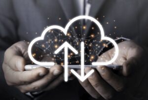 Hands holding a smartphone display a digital cloud hologram with arrows indicating upload and download.