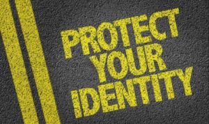 Text PROTECT YOUR IDENTITY stenciled in yellow on a dark, textured surface with yellow lines next to the text, emphasizing the importance of Identity Theft Protection.