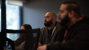 Three individuals with certifications attentively participating in a meeting or presentation.