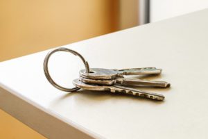 A key ring with four silver keys lying on a light-colored tabletop.