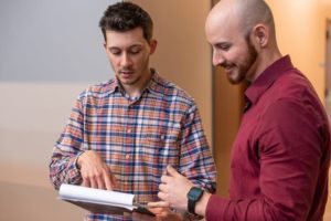 Two men in IT services casual business attire reviewing a document together.