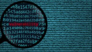 A magnifying glass zooms in on the word "vulnerability" in red amidst a sea of blue alphanumeric code, highlighting the critical nature of unpatched vulnerabilities.