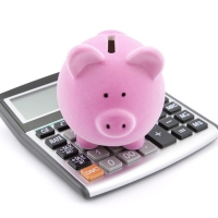 A piggy bank standing on a calculator. 