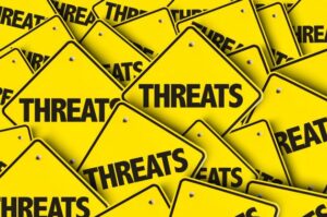 A multitude of yellow caution signs with the word "THREATS" written in bold black letters, overlapping each other—an eerie reminder for IT teams to stay vigilant.
