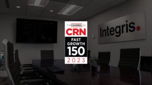 A conference room with a large screen and signage displaying "CRN Fast Growth 150 2023" over a table with chairs. The wall has a sign that reads "Integris.