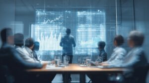 A group of people in a conference room watches a person standing and presenting data charts and graphs on a large transparent screen during an important assessment.
