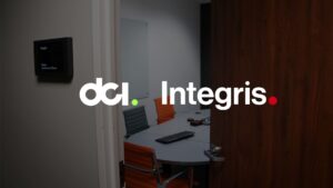 The image shows the partially open door of a conference room. The door sign next to it reads "dcI Integris," with the same name and logo further imposed on the image. Inside the conference room are sleek chairs, a long table with office supplies, and a wall-mounted screen.
