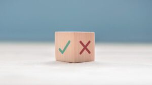 A wooden block displays a green check mark on one side and a red X mark on the adjacent side.