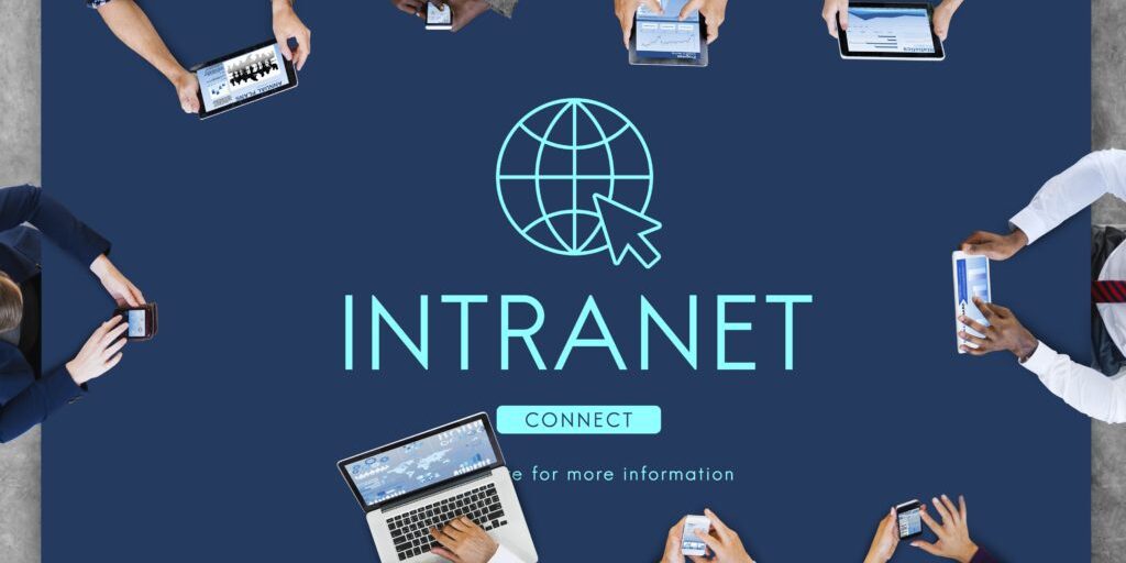 A diverse group of people sit around a table, each engaged with various electronic devices. At the center of the table is a large "INTRANET" graphic featuring a globe icon and the word "CONNECT," reminiscent of SharePoint Intranet platforms.