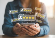 Person holding a smartphone with digital five-star rating icons floating above, symbolizing online reviews and customer feedback.