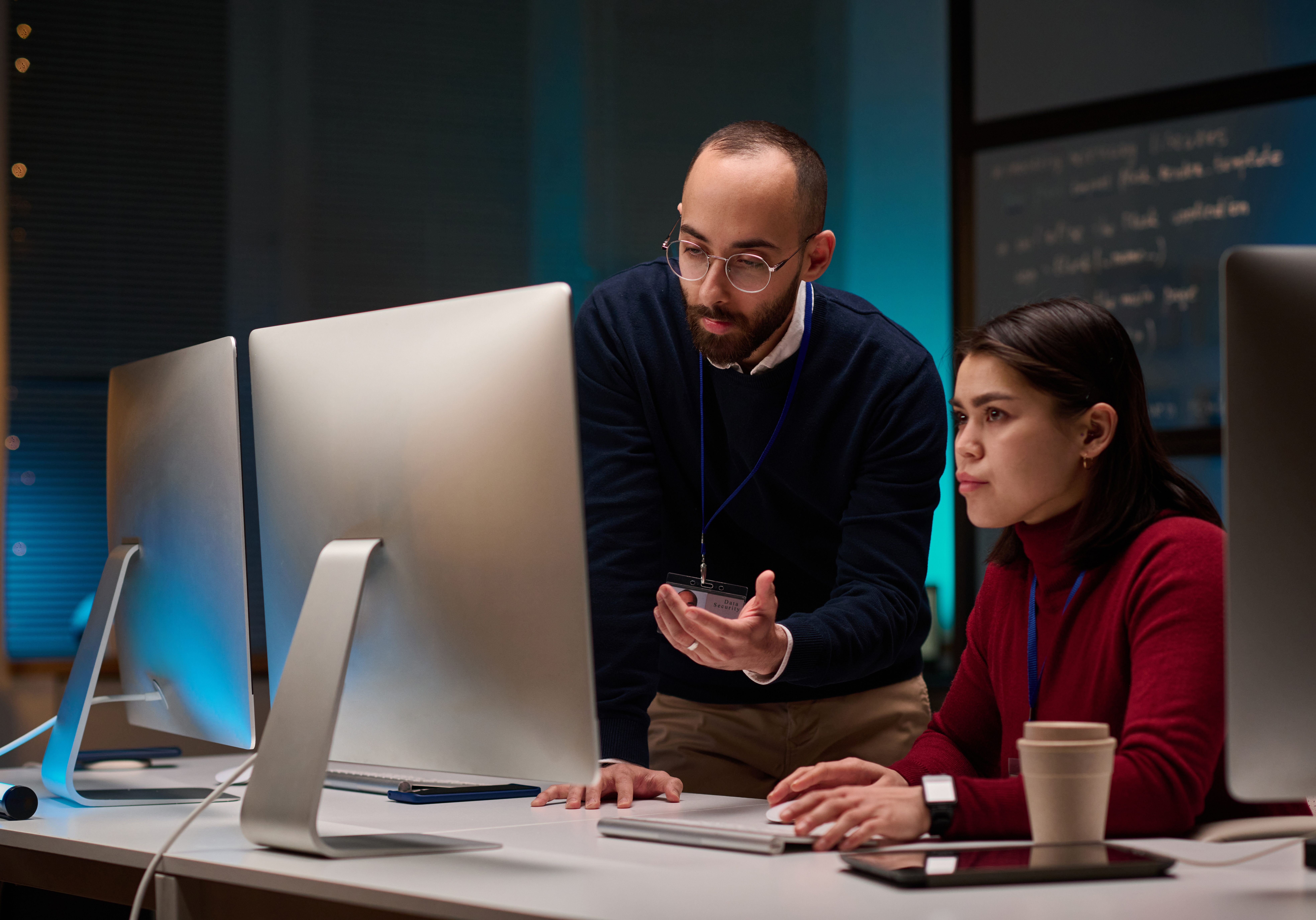 Minimal portrait of two people using computers while working in cybersecurity department with blue lights