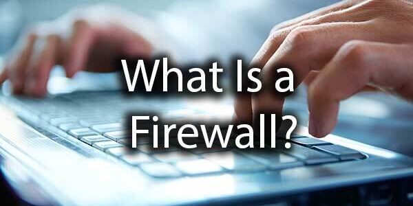 Hands typing on a laptop keyboard with the text "What Is a Firewall?" overlaid on the image.