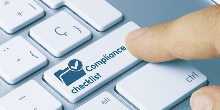 A finger is pressing a key labeled "Compliance checklist" on a white keyboard.