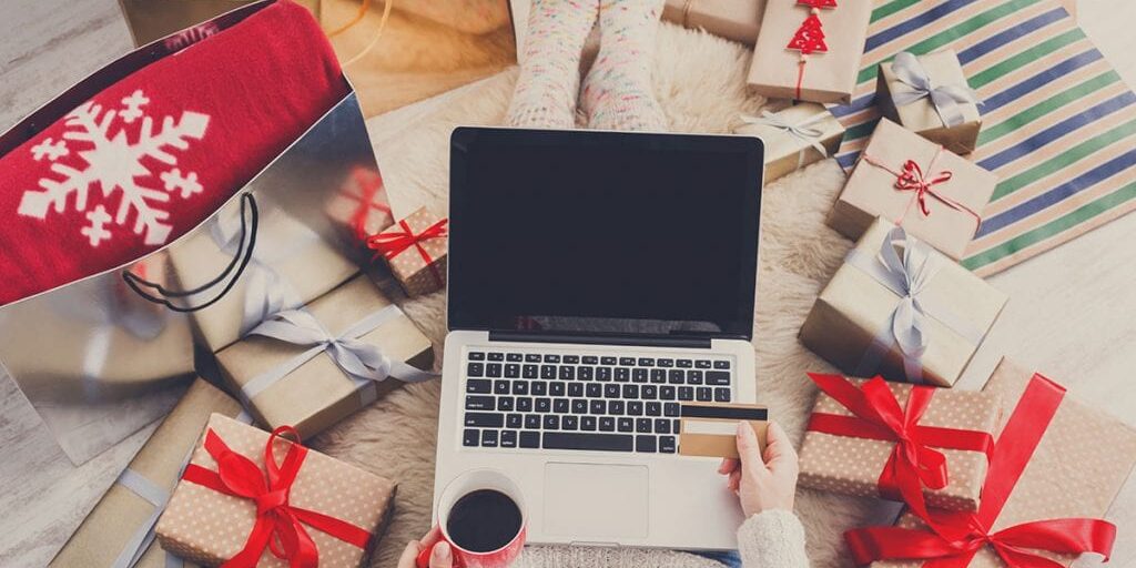 Woman makes christmas shopping online with laptop, above view