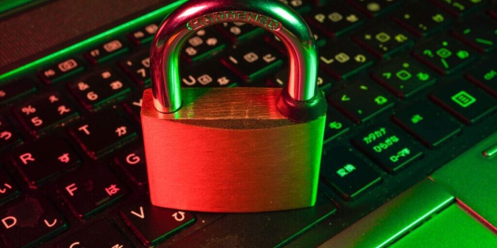 A padlock placed on a laptop keyboard, illuminated by green and red lights, symbolizing digital security and data protection.