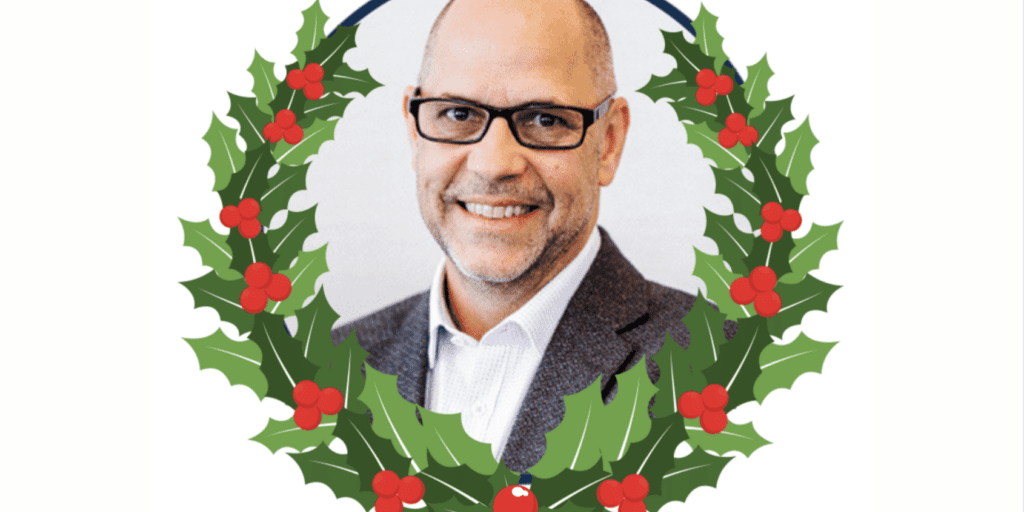Man wearing glasses smiling inside a holly wreath illustration with red berries.