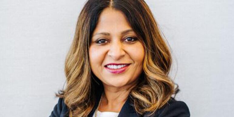 A woman with shoulder-length hair, wearing a dark blazer and smiling warmly.