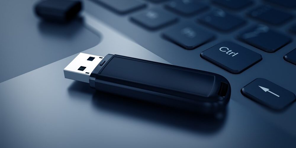 Close-up of a black USB flash drive placed on a laptop keyboard.