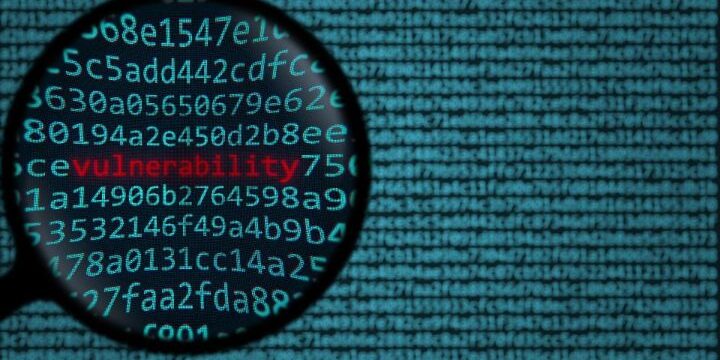A magnifying glass zooms in on the word "vulnerability" in red amidst a sea of blue alphanumeric code, highlighting the critical nature of unpatched vulnerabilities.