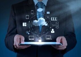A person in a suit holds a tablet displaying holographic technology icons related to cloud computing and data security.