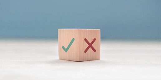 A wooden block displays a green check mark on one side and a red X mark on the adjacent side.