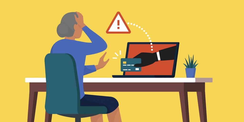 An elderly person sits at a table with a laptop displaying a warning sign and a hand holding a credit card, symbolizing online fraud.