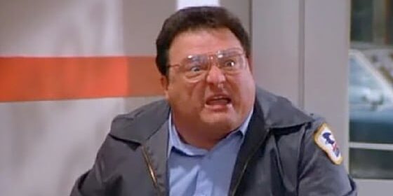 A man in a mailman outfit making a funny face.