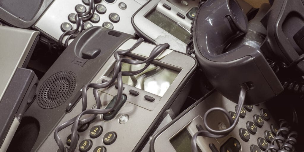 A tangle of old, dusty business phone systems in a box.