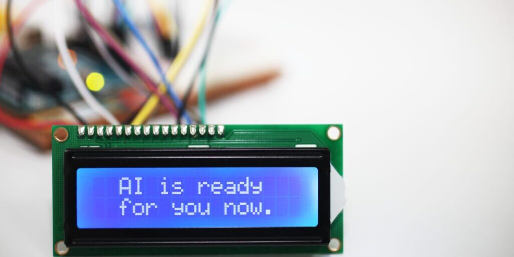 Close-up of an electronic display reading “AI is ready for you now,” with blurred wires in the background, symbolizing AI readiness for banks.