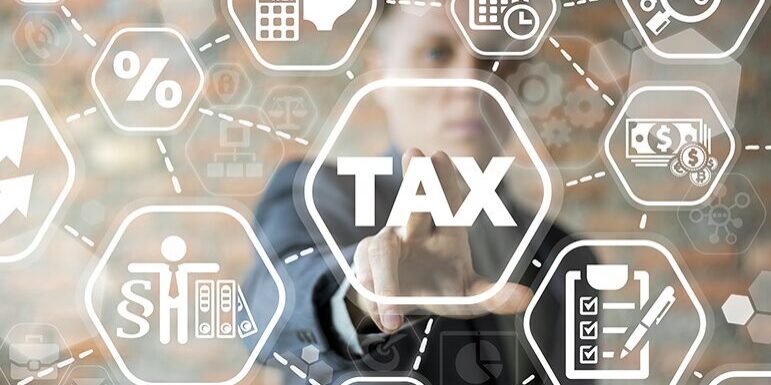 A person touches a virtual screen with the word "TAX" and various related icons, including a calculator, clipboard, graphs, and calendar.