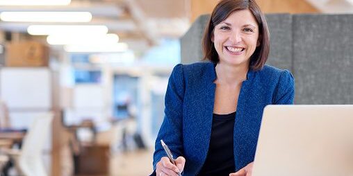 Busineswoman smiling broadly while working in her office cubicle